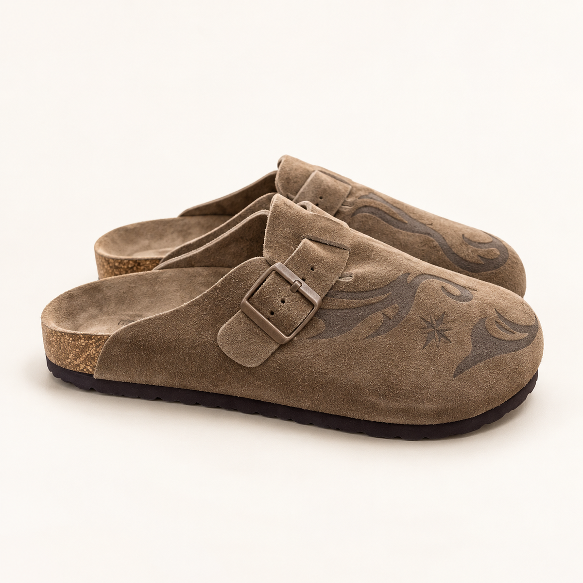 Chocolate suede buckle clogs on warm off-white studio background